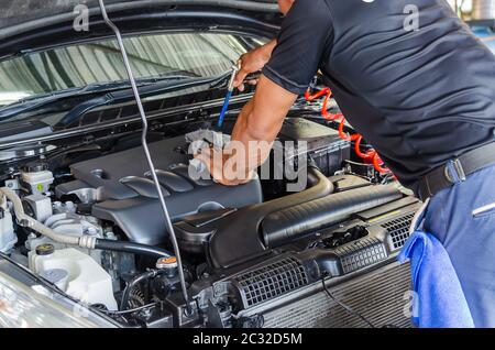 Le mécanicien contrôle le moteur.le homme tenant les mains efface le moteur.le mécanicien utilise un pistolet à air comprimé pour nettoyer le moteur. Banque D'Images