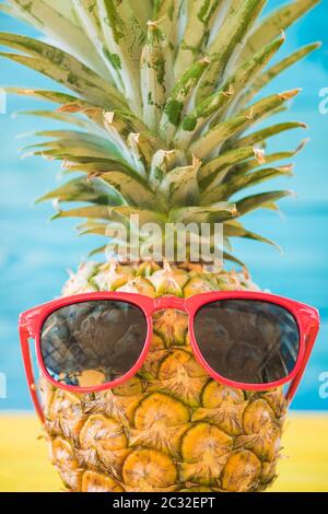 Maison de l'ananas ont lunettes bleu sur fond de bois, concept de vacances tropicales Banque D'Images