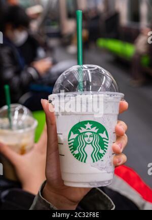 Fille tenant et buvant une boisson Starbucks, Kyoto, Japon dans un train de banlieue. Banque D'Images