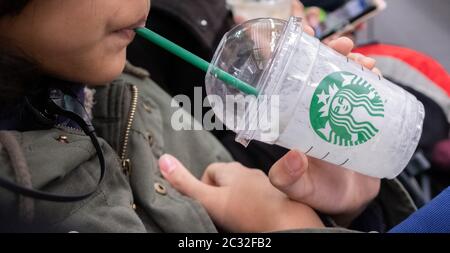 Fille tenant et buvant une boisson Starbucks, Kyoto, Japon dans un train de banlieue. Banque D'Images