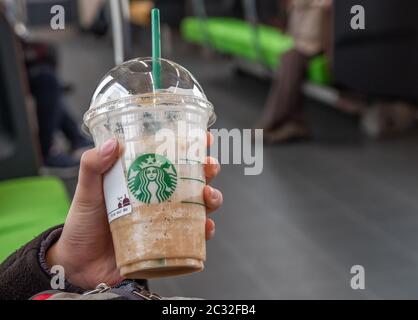 Fille tenant et buvant une boisson Starbucks, Kyoto, Japon dans un train de banlieue. Banque D'Images