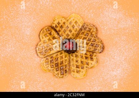 Gaufres maison avec sucre en poudre, une boule de glace à la vanille et une cerise sur fond rose, image isolée de la nourriture. Banque D'Images