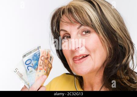 Portrait-tête d'une femme mûre tenant plusieurs BILLETS D'EURO dans sa main à côté de sa tête et regardant la caméra avec sa langue qui lui a fait tourner ses lèvres ag Banque D'Images