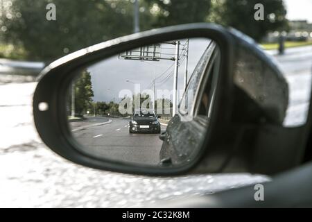 La réflexion dans le miroir. Une voiture de sport noire est à la recherche d'une autre voiture. Banque D'Images