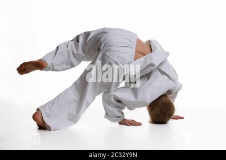 Judo garçon qui fait de l'échauffement se tournoyant autour de lui tout en se tenant sur sa tête Banque D'Images