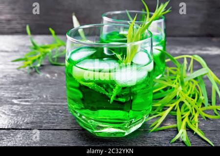 Limonade à l'estragon avec glace dans deux verres, brindilles à l'estragon sur fond de planche en bois noir Banque D'Images