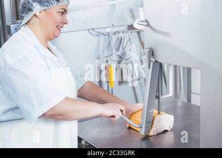 Boucherie femme utilisant la scie pour couper la viande dans sa boucherie pour la vente Banque D'Images