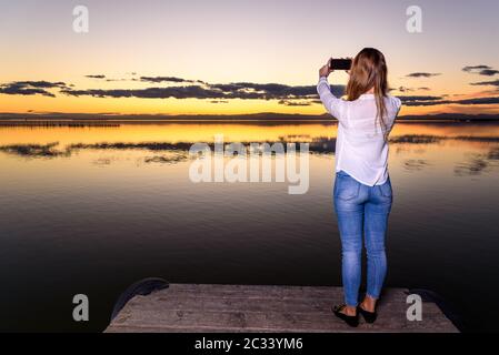 Jeune fille au coucher du soleil en prenant un smartphone selfies avec elle, la visite de l'Albufera de Valence, une réserve naturelle du lac. Banque D'Images