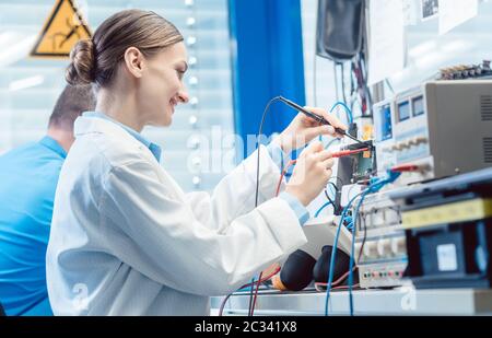 Équipe d'ingénieurs, femme et homme, qui testent et mesurent ensemble un produit électronique dans le laboratoire Banque D'Images