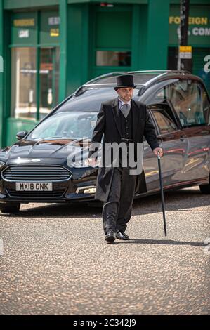 Alloa, Royaume-Uni. 18 juin 2020. Le directeur funéraire marche devant le corbillard portant le corps de Norman Alexander à travers les rues.Alloa résidents sont venus pour payer leurs respects à un homme local Norman Alexander, qui est décédé à l'âge de 90 ans le 5 juin 2020. Norman était originaire d'Aberdeenshire mais est venu à Alloa pour travailler à comme un coop, avant de devenir un ironmongers, il a fait beaucoup pour la région. Son cercueil a été tourné autour d'Alloa avant d'être conduit au crématorium de Falkirk. Crédit : SOPA Images Limited/Alamy Live News Banque D'Images