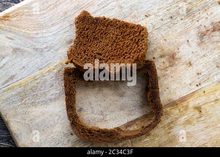morceaux de pain noir foncé faits de farine de seigle, gros plan de la nourriture sur une surface en bois, la pulpe séparée de la croûte Banque D'Images