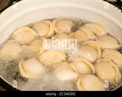 Les boulettes de la pâte à viande sont bouillies dans de l'eau bouillante. Banque D'Images