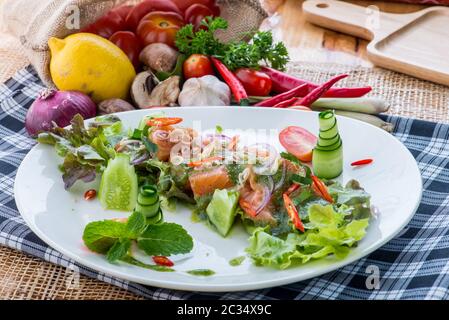 Salade de saumon frais avec légumes, salade saine avec feuilles de laitue mélangées sur un plat blanc sur une table rustique ancienne, recette facile, vue de dessus style thaïlandais Banque D'Images