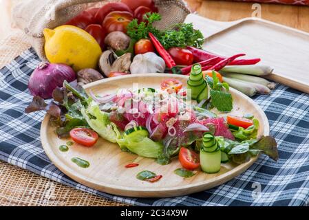 Salade de saumon frais avec légumes, salade saine avec feuilles de laitue mélangées sur un plat blanc sur une table rustique ancienne, recette facile, vue de dessus style thaïlandais Banque D'Images