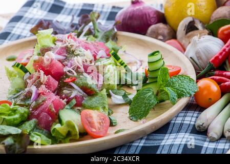 Salade de saumon frais avec légumes, salade saine avec feuilles de laitue mélangées sur un plat blanc sur une table rustique ancienne, recette facile, vue de dessus style thaïlandais Banque D'Images