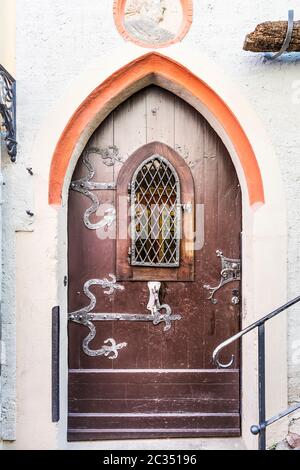 Portail d'entrée en pierre historique avec arche pointue. Garnitures de porte avant et extérieure marron et abîmé, et trappe barrée. Banque D'Images