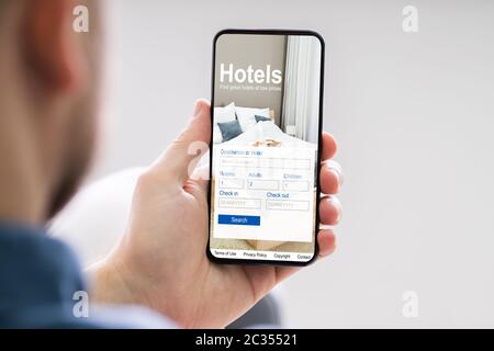 Close-up d'une personne titulaire d'un téléphone intelligent à l'aide de l'application en ligne Prix bas Hôtels Banque D'Images