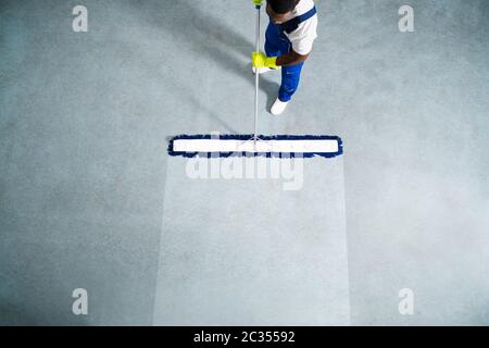 Homme Avec Balai À Franges Et Panneau De Sol Humide Banque D'Images