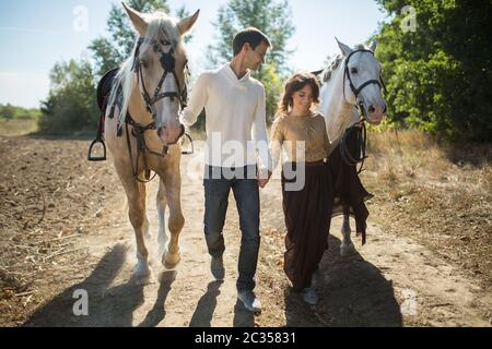 Jeune couple en train de marcher dans un endroit pittoresque avec les chevaux Banque D'Images