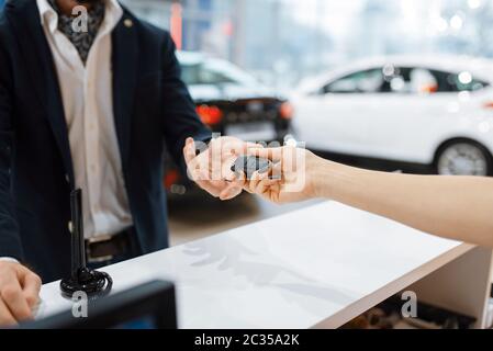 Man prend la clé de la nouvelle voiture dans la concession automobile. Client et vendeur dans la salle d'exposition de véhicule, homme achetant le transport, bus de concessionnaire automobile Banque D'Images