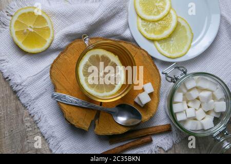 Tasse en verre transparent avec thé à la menthe sur un support en bois, à côté d'un bol à sucre avec des cubes de sucre, un citron en tranches et une cuillère. Banque D'Images