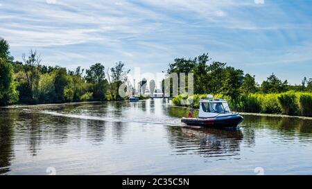 Le bateau gonflable à moteur flotte sur une rivière, entouré de roseaux et de tentatives, belle journée d'été sur la marina de bateaux de Szczecin, Pologne Banque D'Images