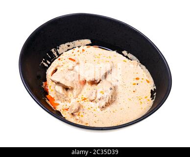 Cuisine géorgienne - portion de Satsivi (apéritif froid épicé de poulet en sauce aux noix) dans un bol noir isolé sur fond blanc Banque D'Images