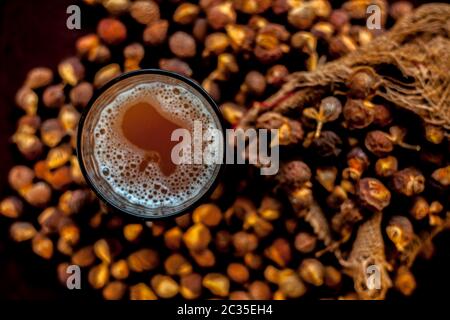 Gros plan de la soapnut fraîche brute sur une surface brune avec sa solution ou son liquide dans un verre le long de celle-ci. Banque D'Images