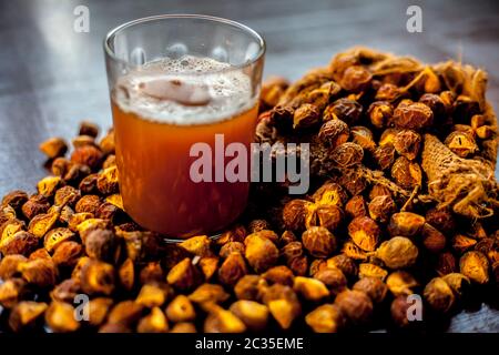 Gros plan de la soapnut fraîche brute sur une surface brune avec sa solution ou son liquide dans un verre le long de celle-ci. Banque D'Images