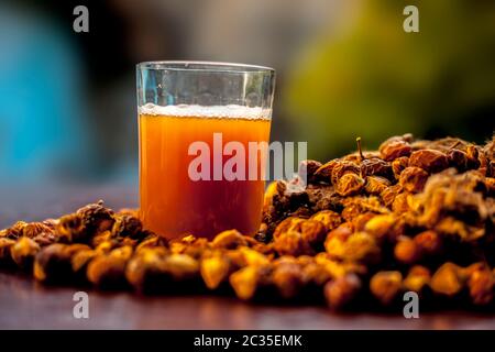 Gros plan de la soapnut fraîche brute sur une surface brune avec sa solution ou son liquide dans un verre le long de celle-ci. Banque D'Images