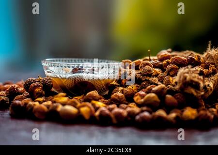 Gros plan de la soaécrou brut et de sa solution dans un bol en verre sur une surface en bois marron, plan avec un arrière-plan bokeh flou. Banque D'Images