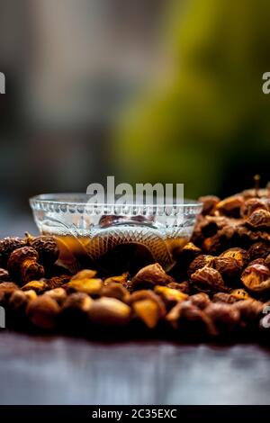 Gros plan de la soaécrou brut et de sa solution dans un bol en verre sur une surface en bois marron, plan avec un arrière-plan bokeh flou. Banque D'Images
