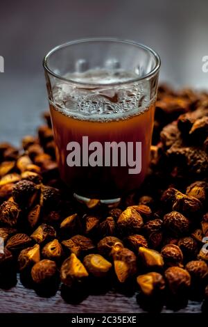 Gros plan de la soapnut fraîche brute sur la surface brune avec sa solution ou son liquide dans un verre le long de celle-ci. Banque D'Images