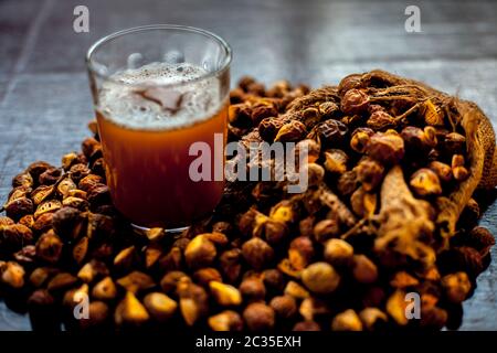Gros plan de la soapnut fraîche brute sur la surface brune avec sa solution ou son liquide dans un verre le long de celle-ci. Banque D'Images