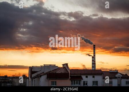 De la vapeur ou de la fumée s'échappe des tuyaux. Centrale thermique de la ville. Paysage au coucher du soleil ou à l'aube dans la ligne d'horizon Banque D'Images