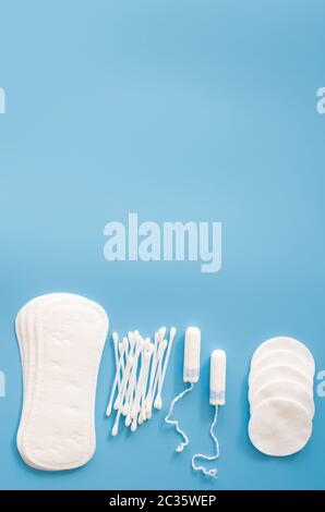 Accessoires d'hygiène féminine. Concept d'hygiène féminine pendant la menstruation. Tampon sanitaire, tampons, bourgeons de coton et tampons de coton sur fond bleu. Banque D'Images