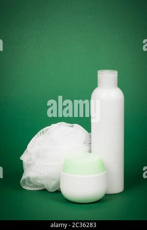 Le gel douche blanc et l'éponge de bain sont sur fond vert, concept de soins du corps. Banque D'Images