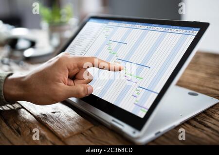 Close-up of a woman avec diagramme de Gantt sur l'ordinateur portable sur le bureau Banque D'Images