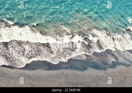 Vue de dessus de loin sur l'océan Atlantique avec une couleur bleu-vert vif et de l'eau en mouvement avec une petite partie de plage gris foncé de sable de lave dans le Banque D'Images