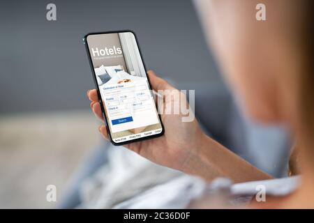 Close-up d'une personne titulaire d'un téléphone intelligent à l'aide de l'application en ligne Prix bas Hôtels Banque D'Images
