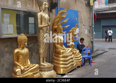 Des statues de Bouddha se trouvent devant une usine de statues de Bouddha et d'autres objets religieux dans une voie latérale au large de Bamrung Muang Road, Bangkok, Thaïlande Banque D'Images