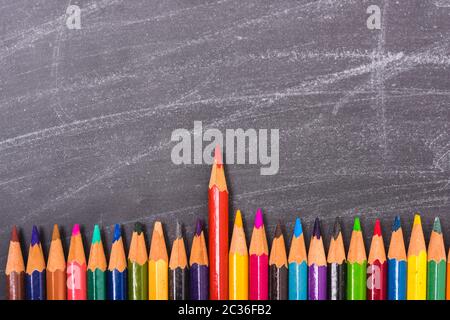 Crayons de couleur rouge qui se détache de la foule sur tableau noir et tableau a Banque D'Images