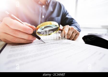 Close-up d'un juge à la main au document avec loupe Banque D'Images