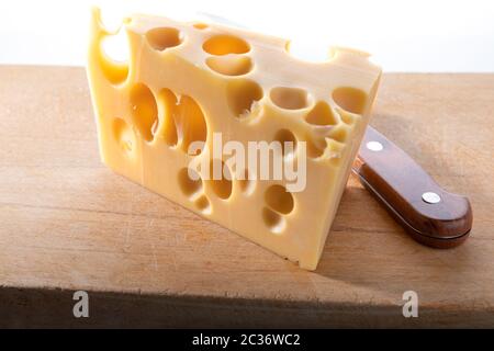 Morceau de fromage sur une planche en bois avec un couteau. Banque D'Images