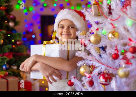 Bonne fille avec un cadeau dans un arbre de Noël blanc Banque D'Images