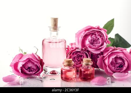 Eau de rose parfumée dans une bouteille de verre, huile et roses. Banque D'Images