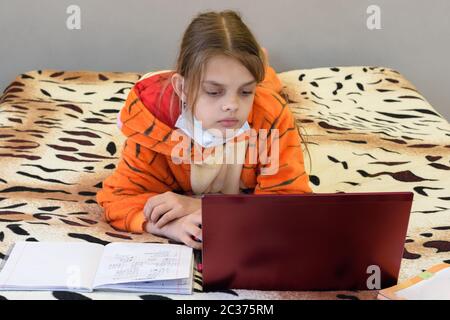 Une fille malade en quarantaine apprend à distance à utiliser un ordinateur portable Banque D'Images