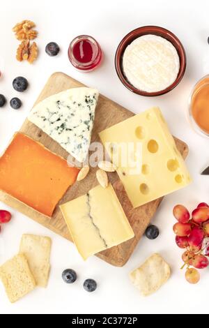Plateau de fromages, plan plat sur fond blanc. Fromage bleu, fromage hollandais et autres, une variété de fruits et de noix Banque D'Images
