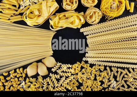 Design italien des pâtes avec espace de copie, une couche plate d'une variété de types de pâtes, prises de dessus sur un fond noir avec un lieu Banque D'Images