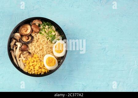 Hommes. Nouilles soba avec œufs, shiitake et champignons enoki, et légumes, tournées d'en haut sur un fond bleu avec copyspace Banque D'Images